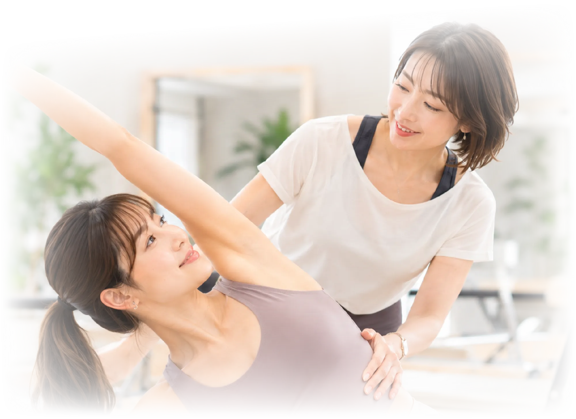 トレーナーが利用者の動きを支えるマシンピラティスのレッスン風景